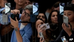 People take photos of the iPhone 15 Pro phones during an announcement of new products on the Apple campus in Cupertino, Calif., Sept. 12, 2023. 