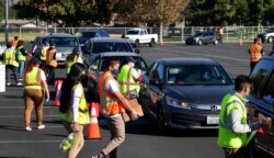 FILE - In this file photo taken on Dec. 04, 2020, food is loaded as drivers in their vehicles wait in line on arrival at a "Let's Feed LA County" food distribution hosted by the Los Angeles Food Bank in Hacienda Heights, California.