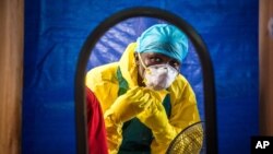 FILE -A healthcare worker dons protective gear before entering an Ebola treatment center in the west of Freetown, Sierra Leone, Oct. 16, 2014..