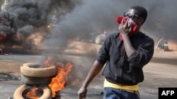 Un homme se couvre la bouche et le nez d'un la fumée noire de pneus brulés à Niamey après que la police a tiré des gaz lacrymogènes pour disperser une manifestation d'opposition interdit dans la capitale du Niger, le 18 janvier 2014.