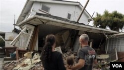 Maree (kiri), Jasmine (tengah) dan Norm Butcher memandangi rumah mereka di Christchurch, Selandia Baru, yang rubuh akibat gempa.
