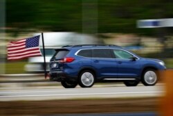 A motorist from Massachusetts flies an American flag ahead of the Memorial Day holiday while traveling on the Maine Turnpike, May 28, 2021, in Kennebunk, Maine.