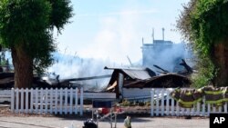 FILE - Firefighters' jackets hang on the fence of the burned-out remnants of Sacred Heart Church on the Penticton Indian Reserve, near Penticton, British Columbia, June 21, 2021. (James Miller/Penticton Herald via AP) 