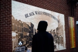 A man looks at a Black Wall Street mural in the historic Greenwood neighborhood of Tulsa, Oklahoma, May 27, 2021, ahead of centennial commemorations of the Tulsa Race Massacre.