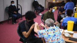 FILE - Members of the public receive a dose of the AstraZeneca/Oxford vaccine at a coronavirus vaccination center at the Fazl Mosque in southwest London, March 23, 2021.