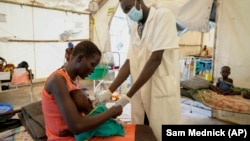 Une mère tient dans ses bras sa fille d'un an souffrant de malnutrition sévère alors qu'elle est suivie par un médecin dans un hôpital géré par Médecins Sans Frontières à Old Fangak, dans l'État de Jonglei, au Sud-Soudan, mardi 28 décembre 2021.