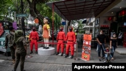 People walk past statues featuring characters from the Netflix series Squid Game at a food court to attract visitors in Surabaya on Oct. 21, 2021.