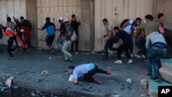 Anti-government protesters run for cover while security forces fire live ammunition in the air to disperse protesters, during ongoing protests, in Khilani Square, Baghdad, Nov. 11, 2019.
