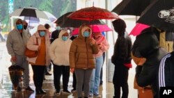 មនុស្ស​ម្នា​ពាក់​ម៉ាស់​មុខ ខណៈ​ពួកគេ​ឈរ​តម្រង់​ជួរ​សម្រាប់​ការ​ធ្វើតេស្ត​កូវីដ១៩ ដោយ​ឥត​គិត​ថ្លៃ​នៅ​ខាង​ក្រៅ​មជ្ឈមណ្ឌល​កម្សាន្ត Lincoln Park ក្នុង​ទីក្រុង Los Angeles កាលពី​ថ្ងៃទី៣០ ខែធ្នូ ឆ្នាំ២០២១។ (AP)