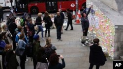 Seorang pria meletakan secarik kertas di antara pesan-pesan untuk memprotes serangan teror di dekat Jembatan London, 8 Juni 2017. 