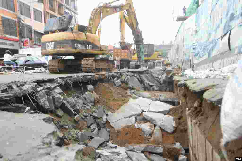 រថ​យន្ត​អេស្កា​វេទ័រ​ជីក​កកាយ​ដី​បន្ទាប់​ពី​រថយន្ត​ចំនួន​បី​គ្រឿង​ផុង​ ស្រុត​ខណៈពេល​មាន​ភ្លៀង​ធ្លាក់​ជោគជាំ​នៅ​ក្បែរ​ការ​ដ្ឋាន​សាងសង់​មួយ​នៅ​​ជិត​ពហុកីឡាដ្ឋាន​ជាតិ​​អូឡាំពិក​នៃ​ខណ្ឌ​ប្រាំពីរ​មករា​ នៅ​ថ្ងៃ​ពុធ ​ទី​០៧ ​ខែ​មិថុនា​ ឆ្នាំ​២០១៦​នេះ​។ ​រថយន្ត​ចំនួន​បី​គ្រឿង​ដែល​គេ​ចត​ចោល​នៅបណ្ដោយ​ផ្លូ​វ​​ជាប់​ការ​ដ្ឋាន​នេះ ត្រូវ​ក្រុម​ហ៊ុន​ការ​ដ្ឋាន​សាងសង់​ស្ទួច​ទៅ​ឲ្យ​ម្ចាស់​ដើម​វិញ។​ (ឡេង ឡែន/VOA )