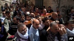 Christian worshipers carry a cross towards the Church of the Holy Sepulcher, traditionally believed by many to be the site of the crucifixion of Jesus Christ, during the Good Friday procession in Jerusalem's Old City, Mar. 29, 2013. 