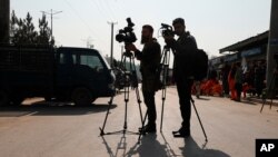FILE - Afghan journalists film at the site of a bombing attack in Kabul, Afghanistan, Feb. 9, 2021.
