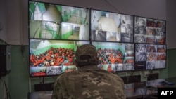 FILE - A fighter with the Syrian Democratic Forces (SDF) monitors on surveillance screens prisoners accused of being affiliated with the Islamic State (IS) group, at a prison in the northeastern Syrian city of Hasakeh, Oct. 26, 2019. 