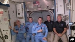 This photo provided by NASA shows Bob Behnken and Doug Hurley, far right, joining the the crew at the International Space Station, after the SpaceX Dragon capsule pulled up to the station and docked May 31, 2020. 
