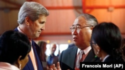 资料照片：2015年12月12日，美国时任国务卿约翰·克里(左)与中国气候变化问题特别代表解振华会谈。（美联社照片）