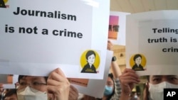 新闻自由倡议者在香港一家法院门前举行集会，其中一幅标语写着“新闻不是犯罪”。（资料照片，2021年4月22日）