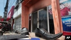 A pair of shoes lie in front of the nightclub Key Club after a fire in Chak Angre Krom village on the outskirts of Phnom Penh, Cambodia, Tuesday, Sept. 8, 2015. A large fire that apparently started in the sound mixing room engulfed the popular nightclub Monday night, an official said. (AP Photo/Heng Sinith)