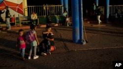 Venezuelan migrant Maryelis Rodriguez and three of her four children wait for a transportation that will take them to the Brazilian border, in Santa Elena de Uairen, Venezuela, April 5, 2023.
