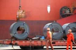 FILE - Workers load steel products for export to a cargo ship at a port in Lianyungang, Jiangsu province, China, May 27, 2020. (China Daily via Reuters)