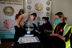Health workers register residents for their first doses of the AstraZeneca vaccine at a COVID-19 vaccination center in the Bankstown suburb of Sydney, Aug. 7, 2021, as Australia's state of New South Wales reported another record day of infections.