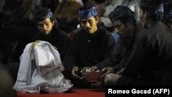 Suku Baduy berdoa di depan seikat padi yang baru dipanen saat upacara di istana Cigugur Pangeran Djati Kesuma, dihiasi dengan buah-buahan yang baru dipanen dalam upacara panen tahunan tradisional selama seminggu yang dikenal sebagai "Seren Taun" di Cigugu