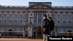 People wearing face masks walk past Buckingham Palace amid the COVID-19 outbreak, in London, Britain, Jan. 22, 2021.