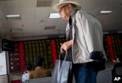 A man leaves as stock investors monitor the stock prices at a brokerage house in Beijing, China, Wednesday, July 8, 2015.