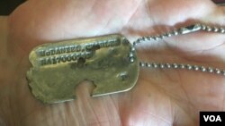 찰스 맥대니얼 주니어 씨가 VOA와의 인터뷰 도중 아버지 찰스 호버트 맥대니얼 상사의 군번줄을 들어 보이고 있다.