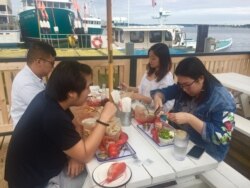 Chinese tourists feast on lobster in Maine. (J.Taboh/VOA)