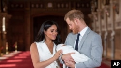 FILE - In this May 8, 2019 file photo Britain's Prince Harry and Meghan, Duchess of Sussex, pose during a photocall with their newborn son Archie, in St George's Hall at Windsor Castle, Windsor, south England. 
