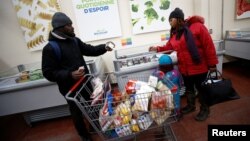 Nigerian refugee claimants Abimbola Ogunyemi, left, and Esther Ogunyemi shop for groceries with their four-year-old daughter Nifemi at the Welcome Hall Mission food bank in Montreal, Feb.13, 2018.