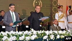 In this handout photograph taken and released by the Pakistan's Press Information Department (PID) on August 14, 2023, Pakistan's President Arif Alvi (C) administers the oath to Anwaar-ul-Haq Kakar (L) as caretaker Prime Minister during an oath-taking cer