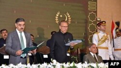 In this handout photograph taken and released by the Pakistan's Press Information Department (PID) on August 14, 2023, Pakistan's President Arif Alvi (C) administers the oath to Anwaar-ul-Haq Kakar (L) as caretaker Prime Minister 
