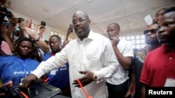 George Weah, mantan pemain sepak bola dan calon presiden Kongres untuk Perubahan Demokratik (CDC), memasukkan surat suaranya di sebuah tempat pemungutan suara di Monrovia, Liberia, 10 Oktober 2017. (Foto: dok).