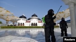 Seorang polisi mengenakan pakaian hazmat menyemprotkan disinfektan di sebuah masjid untuk mencegah penyebaran virus corona (COVID-19) di Banda Aceh, Aceh, 20 Maret 2020. (Foto: Antara via Reuters)