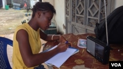 17-year- old Doris Ansumana listening to a radio school program in Freetown, Sierra Leone, Oct, 20,2014- (N.deVries/VOA).