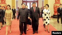 North Korean leader Kim Jong Un and wife Ri Sol Ju, and Chinese President Xi Jinping and wife Peng Liyuan walk together in Beijing, China, in this undated photo released by North Korea's Korean Central News Agency (KCNA) in Pyongyang March 28, 2018.