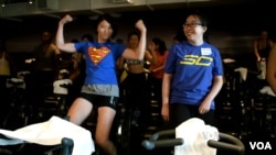 FILE - Women take part in an indoor cycling event in San Mateo, California.