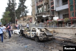 Journalists and civilians stand near the damage after rockets fired by insurgents hit the al-Dabit maternity clinic in government-held parts of Aleppo city, Syria, in this handout picture provided by SANA, May 3, 2016.