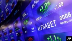 FILE - Electronic screens post prices of Alphabet stock at the Nasdaq MarketSite in New York, Feb. 1, 2016.
