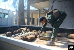In this image provided by the U.S. Army, a Raqqah Internal Security Force member loads unexploded ordnance onto a truck for proper disposal in Raqqah, Syria, on Feb. 19, 2018.