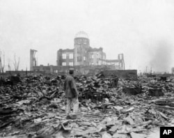 This Sept. 8, 1945 picture shows an allied correspondent standing in the rubble in front of the shell of a building that once was a movie theater in Hiroshima, Japan, a month after the first atomic bomb ever used in warfare was dropped by the U.S.
