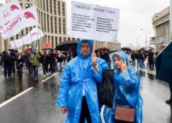 FILE - Vyacheslav Abanichev and Alisa Abanicheva, parents of Sergei Abanichev, hold a poster saying "Free My Son" with the names of all those arrested as they attend an opposition rally in Moscow, Russia, Aug. 10, 2019.