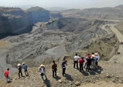 People stand atop a ridge overlooking the scene of a mudslide at a jade gemstone mining site, April 23, 2019, in Hpakant area of Kachin state, northern Myanmar.