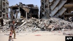 Palestinac drži za ruku malog dječaka dok prolaze pored ruševina uništenih zgrada u izbjegličkom kampu Jabalia, u sjevernom pojasu Gaze, 3. juna 2024.