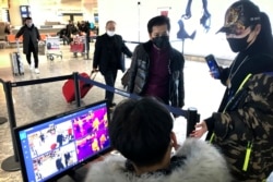 Travelers pass through a health screening checkpoint at Wuhan Tianhe International Airport in Wuhan in southern China's Hubei province, Jan. 21, 2020.