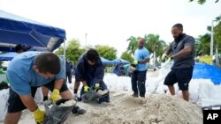 City workers fill sandbags at a drive-thru sandbag distribution event for residents ahead of the arrival of rains associated with tropical depression Fred, Aug. 13, 2021, at Grapeland Park in Miami.