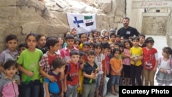 Rami Adham is surrounded by Syrian children who gather near a field school in Aleppo that has since been destroyed, Sept. 2015. (photo courtesy of Rami Adham)