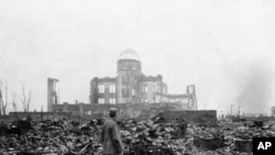 This Sept. 8, 1945 picture shows an allied correspondent standing in the rubble in front of the shell of a building that once was a movie theater in Hiroshima, Japan, a month after the first atomic bomb ever used in warfare. President Barack Obama will visit Hiroshima later this month. (AP Photo/Stanley Troutman)